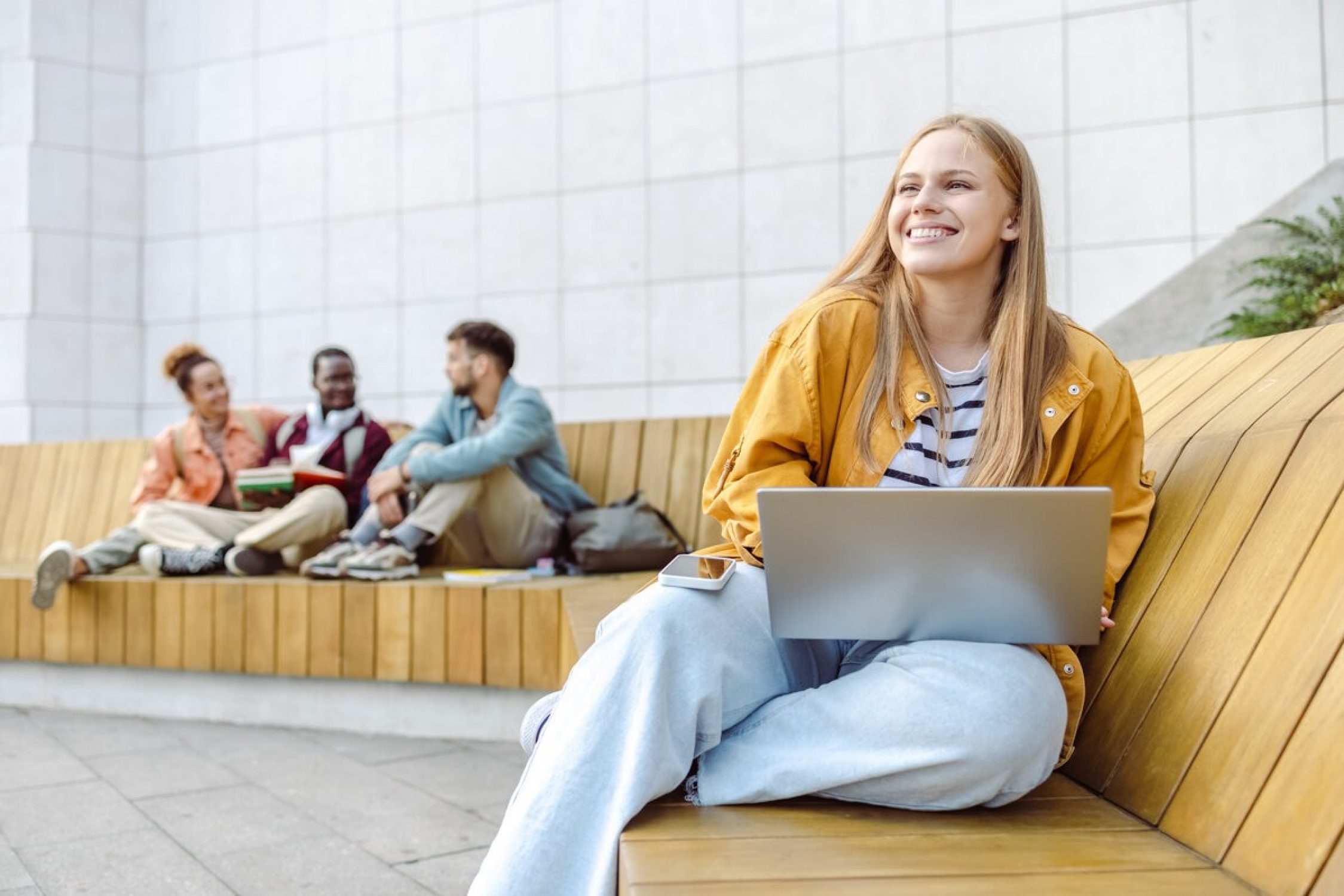 Femme assise sur un banc avec un ordinateur portable.